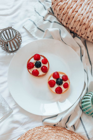 Delicious raspberry tartlets with cream filling on white plate. Fresh fruit tart on white...