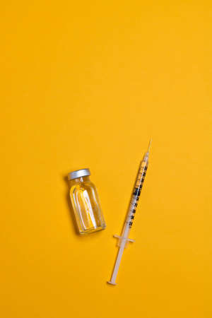 Coronavirus, flu or measles vaccine vial with syringe on yellow background, horizontal banner with copy space. Family immunization concept. Minimal styleの写真素材