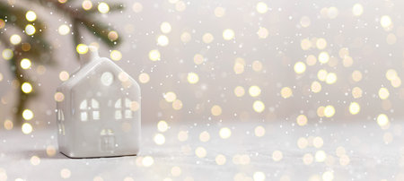 Small toy model house and fir branch on white table with light blurred wall background. Holiday template banner, horizontal compositionの写真素材