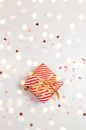 Christmas handmade gift box with gold bow, golden lights on white horizontal background with copy...