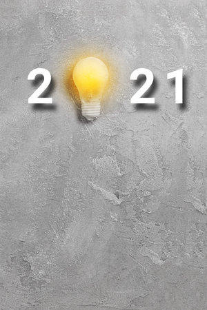 Light yelow bulb idea with 2021 new year text on a gray background. Minimal creative composition,...