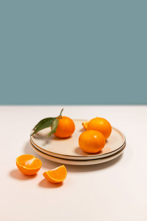Fresh tangerine or clementin fruits on a beige plate with a gold rim on the table. Colorful fruit background Decorative christmas holiday composition with copy space.の写真素材