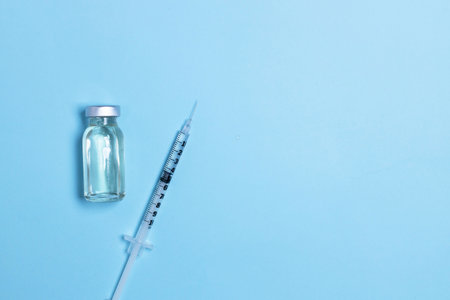 Syringe with medicine from glass vial on light blue background, flat lay, copyspace.の写真素材