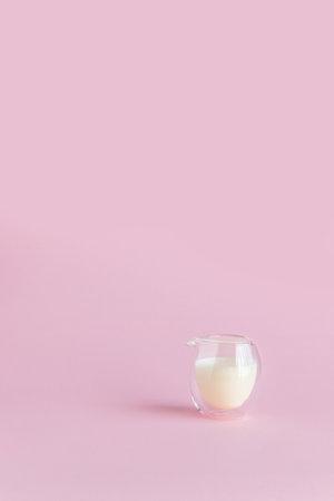 Milk in a glass on a pink background. Vertical photoの写真素材