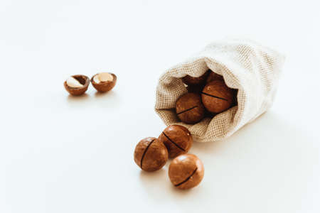 Fresh canvas bag with tasty organic macadamia nuts on white tableの写真素材