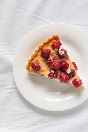 Piece of classic cheesecake with raspberry berries on white plate on the bed. Morning foodの写真素材