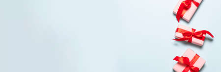 Pink handmade gift boxes with red satin ribbons on blue background for birthday, mother day, merry christmas and new yearの写真素材