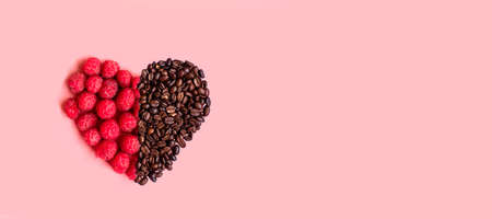 Red raspberries in a heart shape on pink background. Minimal composition.の写真素材
