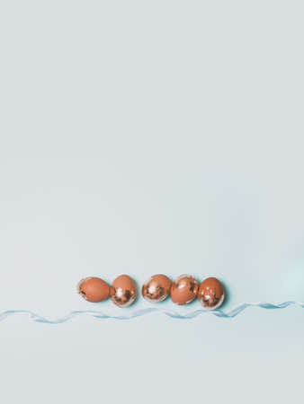 Holiday Easter golden and bronze eggs on blue background. Spring greeting card. Flat lay, top view.の写真素材