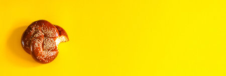 Bitten fresh bun with sugar and sesame seeds with copy space on yellow backgroundの写真素材