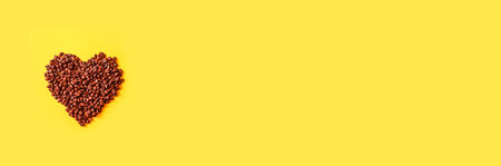 Love of coffee, shape of heart from coffee bean on yellow background. Minimal composition. Flat lay,...