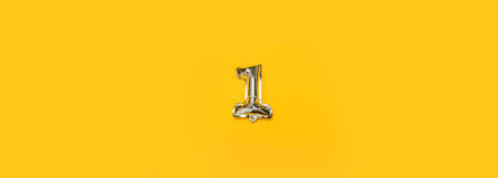 Foil balloon number One isolated on yellow background. Golden numbersの写真素材