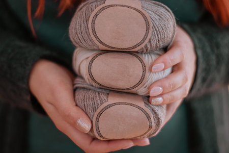 Female hands hold soft colored alpaca yarn with blank labels. Female hobby and leisure knitting...