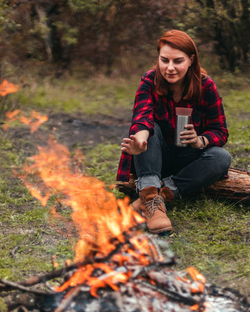 Traveler woman camping in the forest and relaxing near campfire after a hard day. Concept of...
