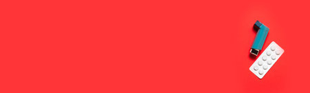 Asthma inhaler, pills and with copy space on red background, top view
