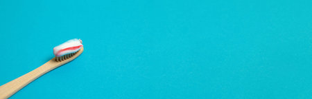 Closeup of natural bamboo toothbrush and toothpaste on blue background with copy space. People teeth...