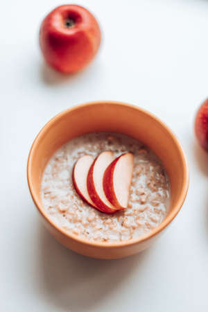 Tasty oatmeal with apple pieces in a yellow bowl on the table. Morning nutritious breakfast.の写真素材