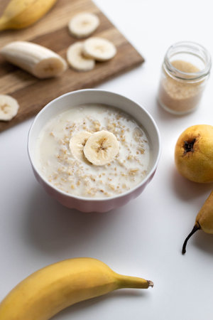 Tasty oatmeal in vegetable milk with slices of banana and pear on the table. Hot and healthy...
