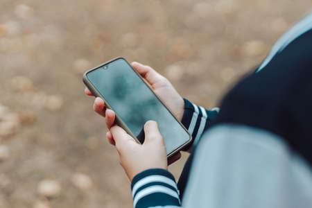 Child hands uses smartphone in summer park or garden outside.の写真素材