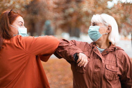 Two people bump elbows to avoid outdoors. Keeping social distance