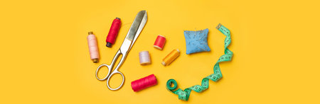 Multi-colored thread spools and sewing accessories on a yellow background.