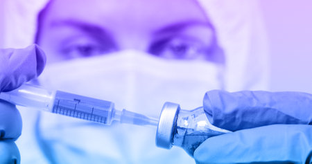Doctor in blue latex gloves fill in syringe with medicine from glass vial for injection of an elderly person in medical laboratoryの写真素材