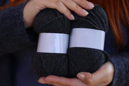 Person hands hold natural color wool alpaca yarn balls with blank labels