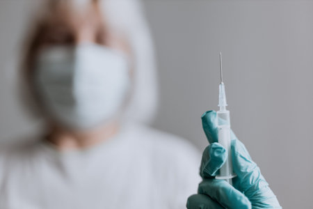 COVID-19 vaccine, female doctor holds syringe and bottle with vaccine for virus infection