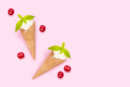 Two Vanilla ice cream cone with mint and cherry on pink background. Copy space. Summer background.