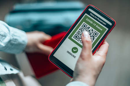 Young girl hand holding a passport, ticket pass and smartphone with digital health passport app for travel during covid-19 pandemic.の写真素材