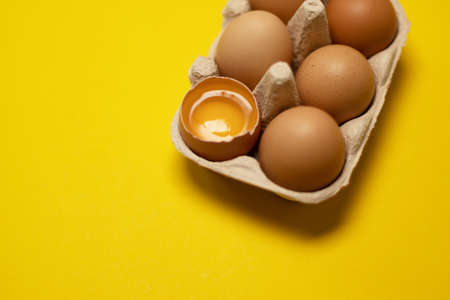 Easter brown chicken eggs in eco basket and one egg on yellow background. Fresh egg on morning breakfast, flat lay, copy space.の写真素材