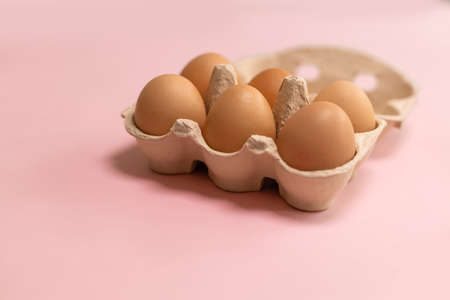 Easter brown chicken eggs in eco basket on pink background. Fresh egg on morning breakfastの写真素材