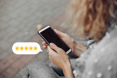 Woman hand using smart phone with icon five star symbol to increase rating of company concept. Customer rating, feedback from consumer for liking product and service conceptの写真素材