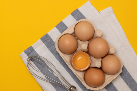 Fresh Easter brown chicken eggs and one broken egg with yolk in eco basket on yellow background