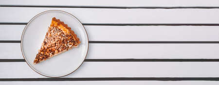 Delicious nut pie piece on white plate on wooden table with copy spaceの写真素材