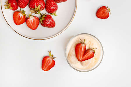 Fresh strawberries in plate with a delicate tiramisu dessert on white wood tableの写真素材