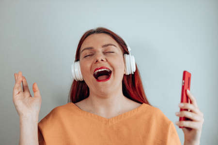 Cheerful woman listening to music and dancing at homeの写真素材
