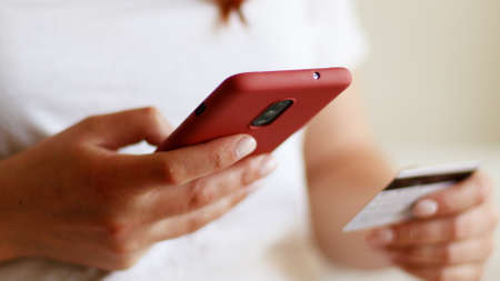Female hands holding a credit card and using smart phone for online shopping. Loan, mortgage and bill paymentの写真素材