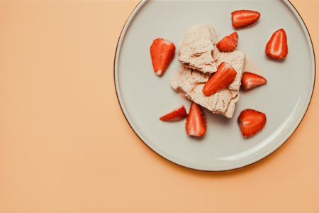 Tasty homemade vanilla ice cream with strawberry on a white plate on beige background. Summer and sweet menu concept.の写真素材