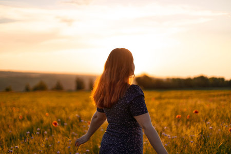 Happy woman with flowers enjoying sunset in field