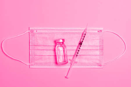 Top view medical composition of syringe with medicine, antibiotic vial and protective mask on minimal pink background. Cosmetology and beauty industryの写真素材