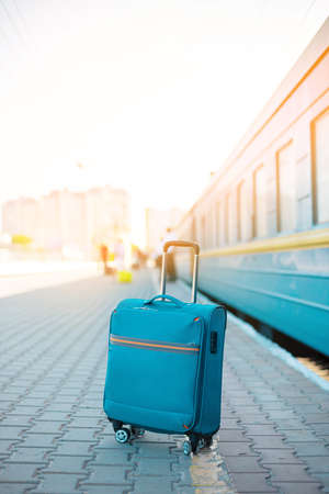 Blue travel luggage on train station near railway on the city street. Adventure, discovery, transport and travel concept background.の写真素材