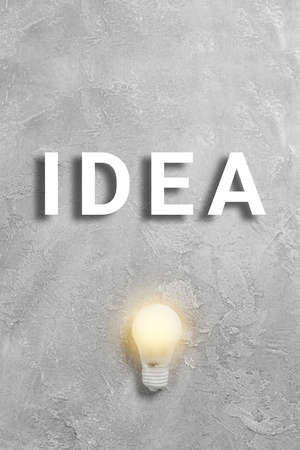 Creative idea text with glowing light bulb on gray background. Minimal art posterの写真素材