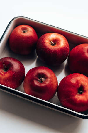 Many red ripe apples in white enamel containerの写真素材