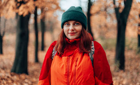 Attractive caucasian woman tourist hiking trip backpack in autumn forest and going camping in nature. Fall landscapeの写真素材