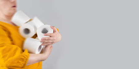 Female hands hold many rolls of toilet paper for their intended use. Hygiene and body care. Stressful shoppingの写真素材