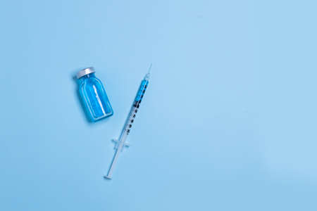 Vial with coronavirus vaccine and syringe with copy space. on light blue background. Top view, flat lay. Vaccination and immunization conceptの写真素材
