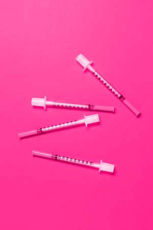Scattered thin cosmetic syringes on pink background. Cosmetology and beauty industryの写真素材