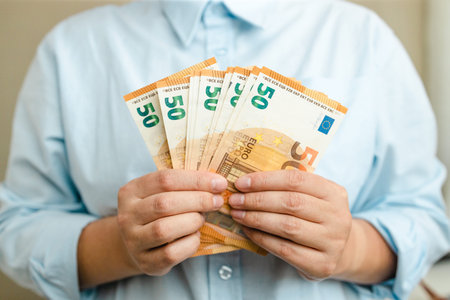 Woman hands with euro money on grey background