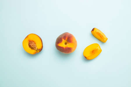 Flat composition with ripe peaches on colored blue background. Fresh organic fruit, vegan food. Harvest concept.の写真素材